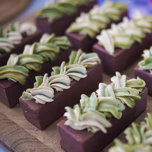 Handcrafted artisan soap bars with green and cream swirl designs on a wooden surface