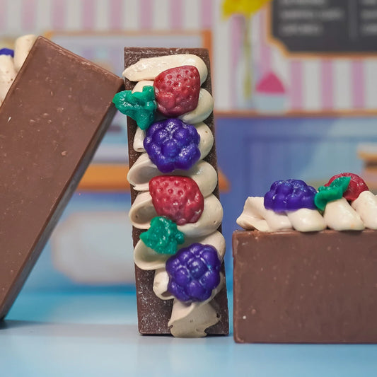 Handcrafted soap bars topped with berry and cream-like decorations, artisan bath product.