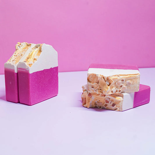 Handcrafted artisan soap bars with pink, white, and gold layers on a pink background