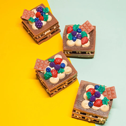Handcrafted artisan soap bars shaped like chocolate and berries on colorful background