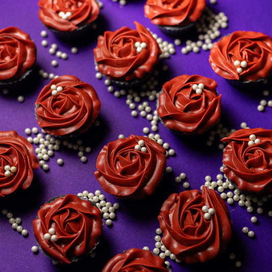 Red rose cupcakes with white pearls on purple background, floral dessert arrangement