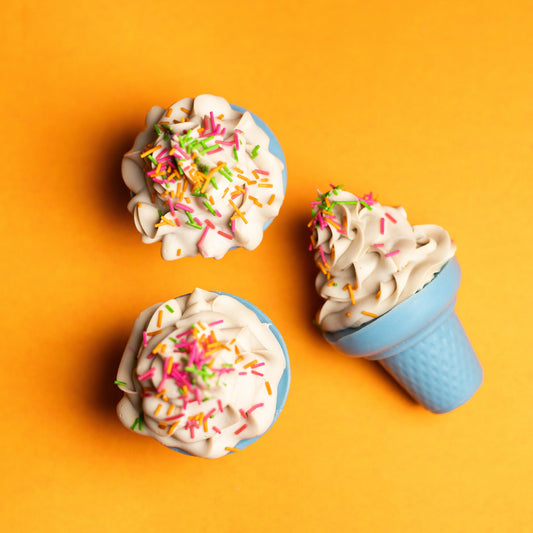 Artisan bath bombs shaped like ice cream cones with colorful sprinkles on orange background