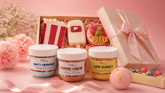 Minimal pastel Salty Secrets gift banner featuring whipped soap jars, handmade soap gifts, bath items, flowers, and a ribbon-wrapped gift box.