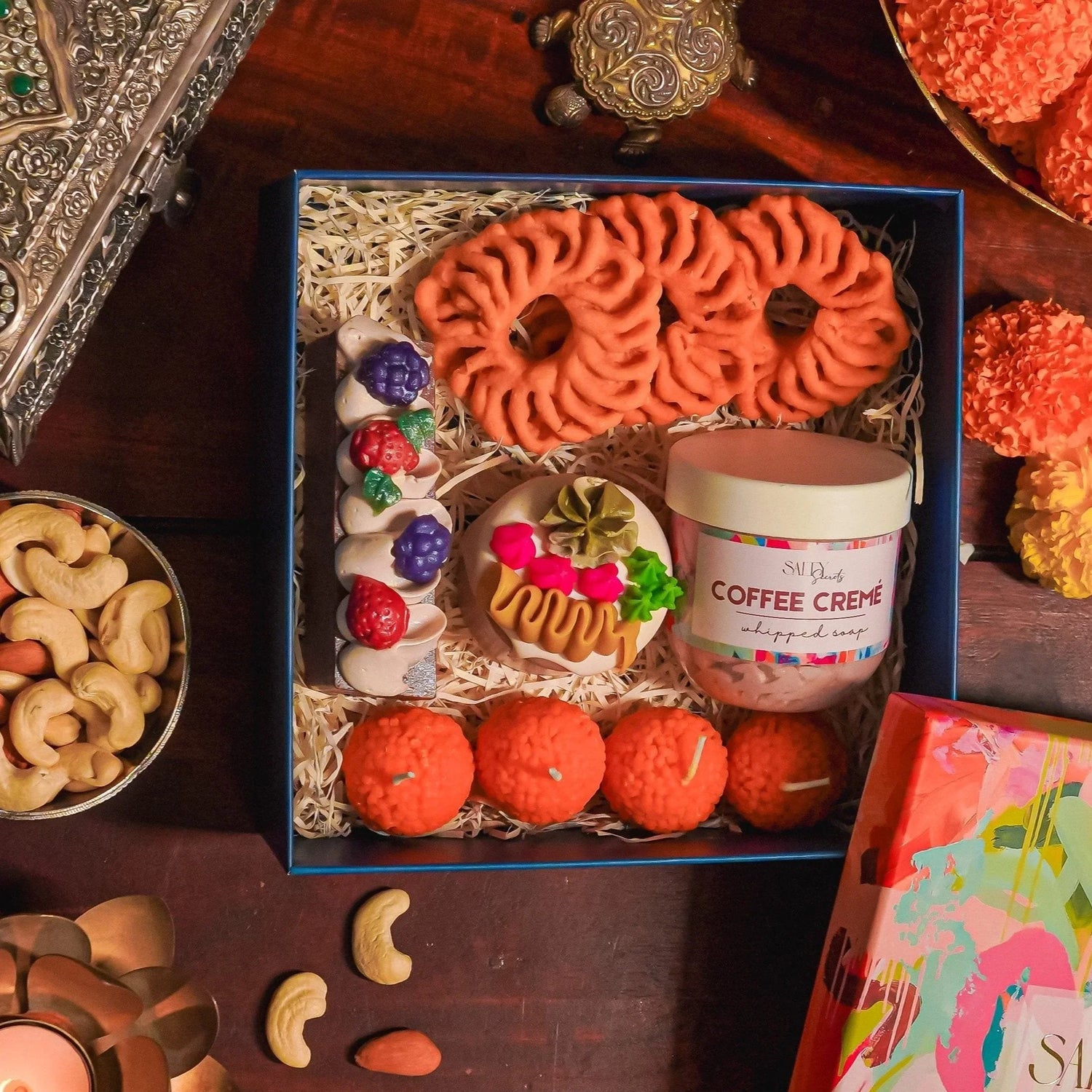 Diwali gift box with artisan soap, whipped soap, decorative flowers, candles, and festive snacks
