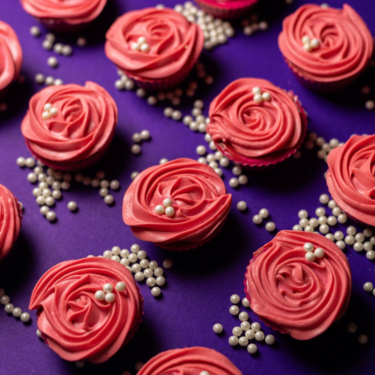 Pink rose-shaped bath bombs with pearl decorations on a purple background